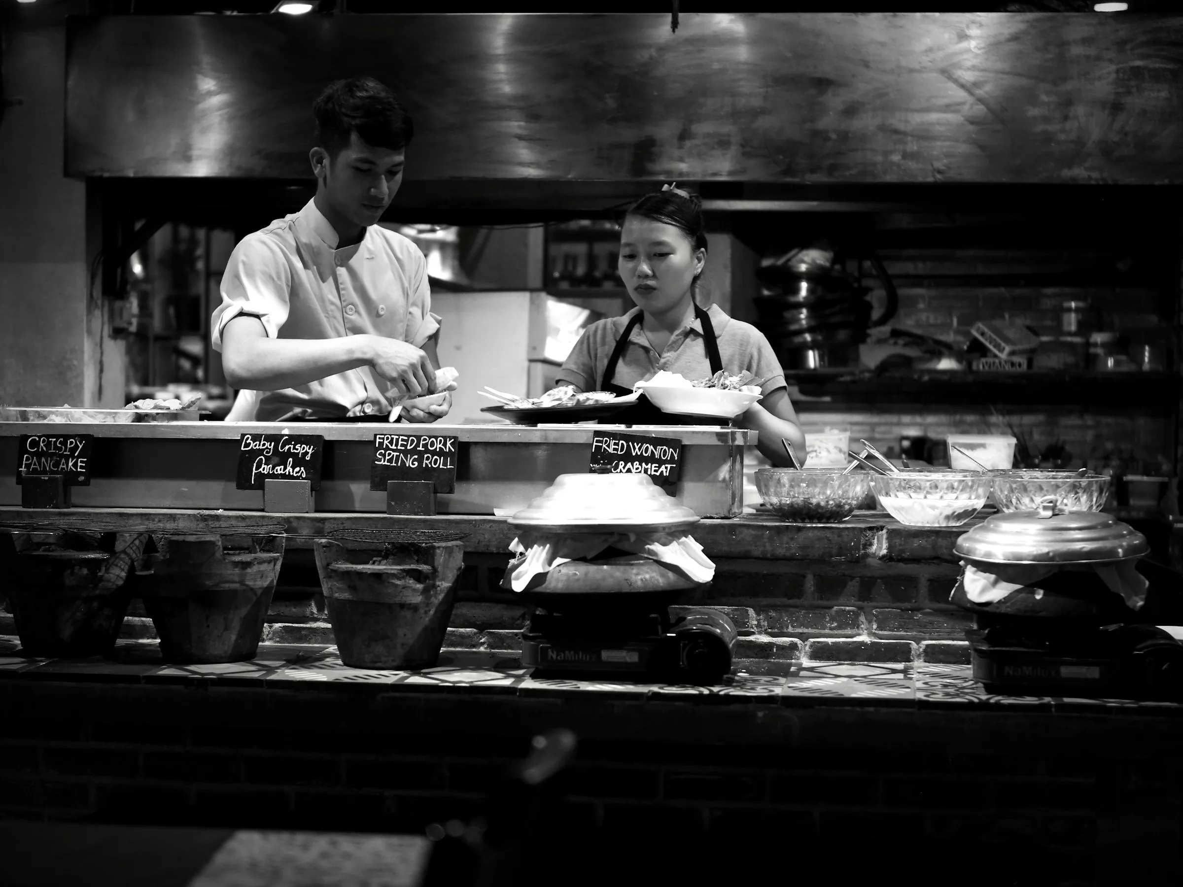 Two cooks working the pass in a restaurant kitchen, black and white