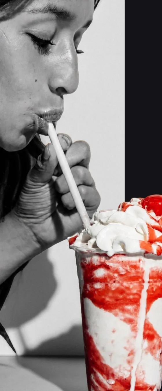 A woman sipping a strawberry milkshake, black and white