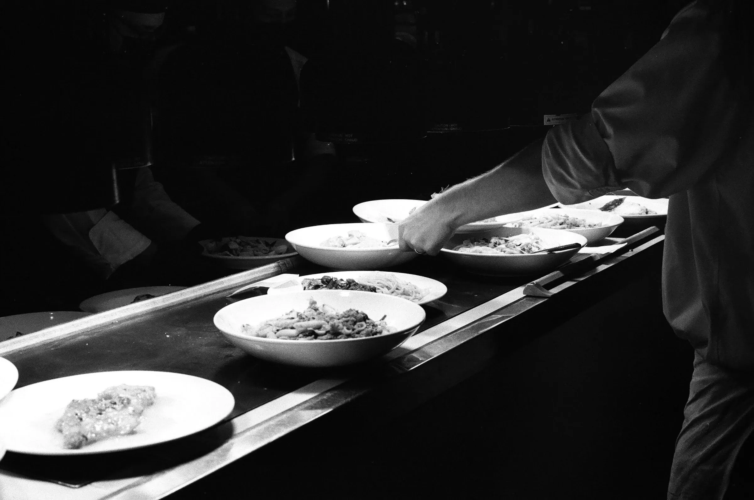 A chef plating a dish in a dimly lit kitchen